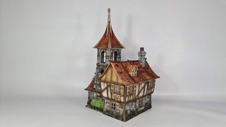 May include: A detailed miniature model of a medieval building, featuring a tall tower with a copper-coloured pointed roof and a lower structure with a red-tiled roof. The walls are painted in shades of brown and beige, with stone detailing. The model has a chimney.
