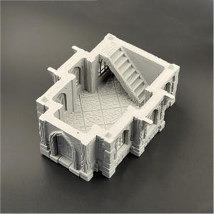 Puede incluir: Modelo de castillo en miniatura gris con detalles arquitect&oacute;nicos intrincados. Incluye una escalera, puertas arqueadas y suelo estampado. El dise&ntilde;o sugiere un tema de fantas&iacute;a o hist&oacute;rico, adecuado para juegos de mesa o exhibici&oacute;n.