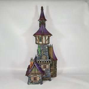 以下が含まれることがあります： 高い塔と複数のレベルを備えた、詳細なミニチュアファンタジー城。 城は紫色の屋根、石壁、小さな窓が特徴です。 デザインには煙突と装飾要素が含まれており、気まぐれな美学を作り出しています。