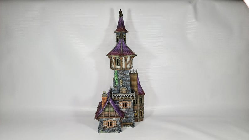 以下が含まれることがあります： 高い塔と複数のレベルを備えた、詳細なミニチュアファンタジー城。 城は紫色の屋根、石壁、小さな窓が特徴です。 デザインには煙突と装飾要素が含まれており、気まぐれな美学を作り出しています。