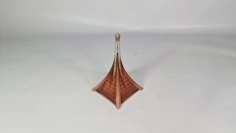 May include: A decorative wooden boat sculpture with a brown hull and a silver mast. The boat has a unique, angular design. The sculpture is set against a white background.