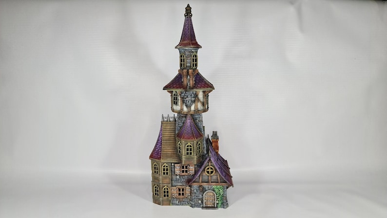 以下が含まれることがあります： 高い塔と複数のレベルを備えた、詳細なミニチュア城。 城は紫色の屋根、石壁、小さな窓が特徴です。 全体的なデザインは気まぐれで装飾的で、展示に適しています。