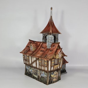 May include: A detailed miniature model of a medieval-style building. The structure features a red-tiled roof, a tall steeple, and multiple windows with shutters. The building is painted in shades of brown, beige, and grey, creating a realistic appearance.