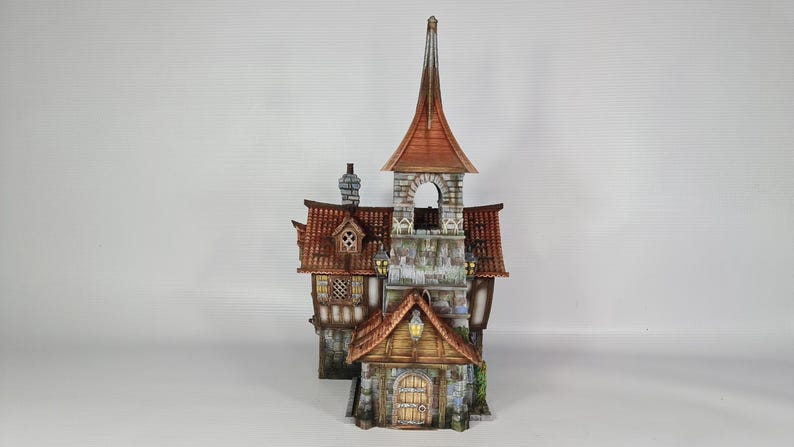 May include: A detailed miniature fantasy building with a tall steeple and multiple levels. The structure features a red tile roof, stone walls, and wooden accents. The building has a small arched doorway and several windows.