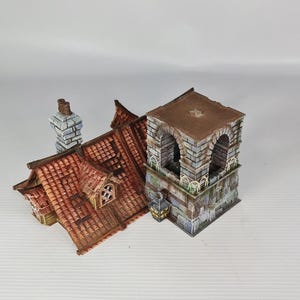 May include: A detailed miniature building model featuring a red-tiled roof, a stone tower, and a chimney. The roof includes a dormer window. The tower has arched openings and a flat roof. The model is painted with realistic details.