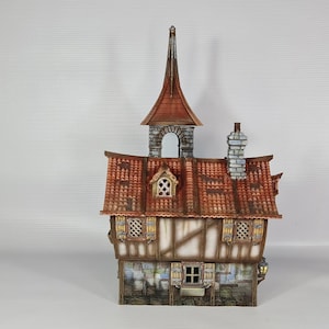 May include: A detailed model of a medieval-style building with a red-tiled roof, a tall steeple, and a chimney. The walls are a combination of light-coloured wood and dark brown beams, with small windows and decorative elements. The model is approximately 20 cm tall.