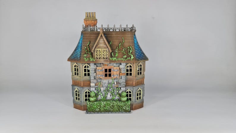 Op de afbeelding: Een gedetailleerd miniatuurhuis met een bruin dak, blauwe accenten en een stenen gevel. De ramen zijn gebogen en het huis is versierd met decoratieve wijnranken en een kleine schoorsteen. Fantasiethema.