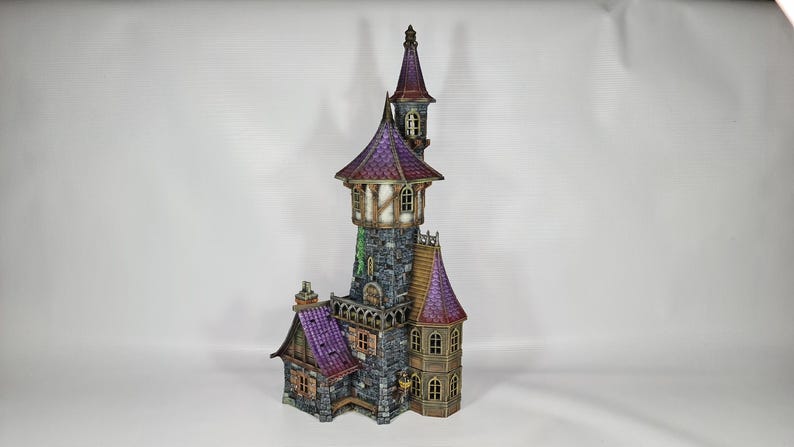 以下が含まれることがあります： 紫と茶色の屋根、石壁、複数の窓を備えた、詳細なミニチュア城。 城には、尖った屋根と小さな塔のある高い塔があります。 全体的なデザインは気まぐれで詳細です。