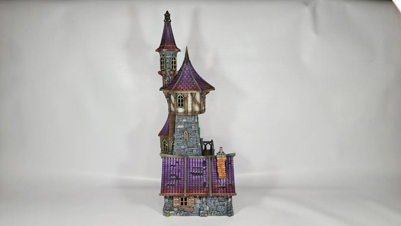以下が含まれることがあります： 高い塔と複数の小塔を備えた、詳細なミニチュアファンタジー城。城は石の基部、紫色の屋根、茶色とタンのアクセントが特徴です。塔には小さな窓と尖った上部があります。