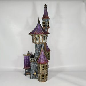 以下が含まれることがあります： 複数の塔と紫色の屋根を持つ、詳細なミニチュア城。 城は石壁、アーチ型の窓、装飾的な要素を持っています。 全体的なデザインは気まぐれでファンタジーをテーマにしています。