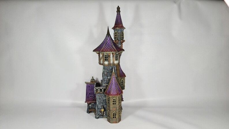 以下が含まれることがあります： 複数の塔と紫色の屋根を持つ、詳細なミニチュア城。 城は石壁、アーチ型の窓、装飾的な要素を持っています。 全体的なデザインは気まぐれでファンタジーをテーマにしています。