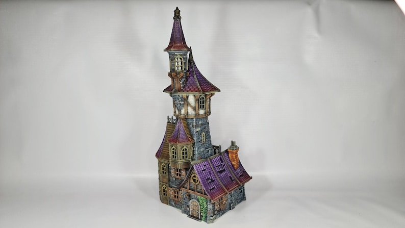 以下が含まれることがあります： 高い塔と複数のレベルを備えた、詳細なミニチュアファンタジー城。 城は紫色の屋根、石壁、小さな窓が特徴です。 全体的なデザインは気まぐれで詳細で、建築要素に焦点を当てています。