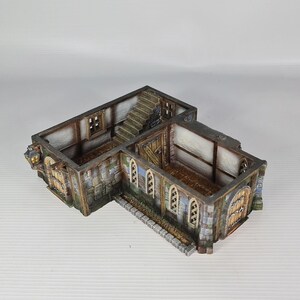 May include: A detailed miniature building, reminiscent of a medieval structure. It features stone walls, wooden doors, and a staircase. The model is painted in shades of grey, brown, and beige, with intricate architectural details.