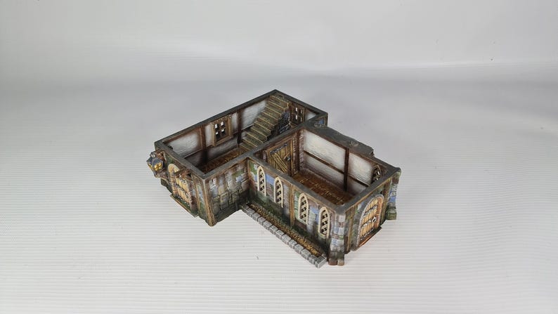 May include: A detailed miniature building, reminiscent of a medieval structure. It features stone walls, wooden doors, and a staircase. The model is painted in shades of grey, brown, and beige, with intricate architectural details.