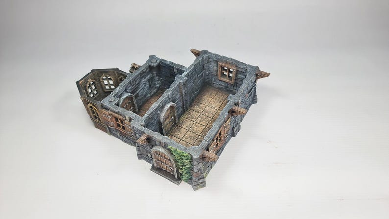 以下が含まれることがあります： グレーの石壁、茶色の木製アクセント、アーチ型のドアを備えた、ミニチュアの城の模型。 この模型は、詳細な窓と、テーブルゲームや展示に最適な質感のあるインテリアを備えています。