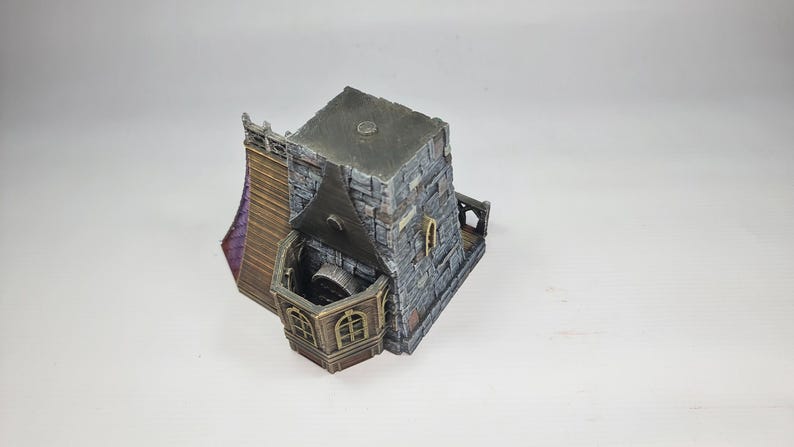 以下が含まれることがあります： 石造りのファサード、濃い灰色の屋根、木製のバルコニーを備えたミニチュアファンタジービル。 アーチ型の窓と紫色のアクセントがあります。 全体的なデザインは、中世またはゴシック様式を連想させます。