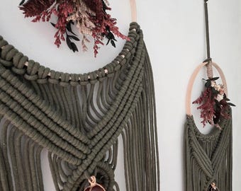 May include: Two wall hangings featuring olive green macrame cord knotted onto wooden hoops. Each hoop is adorned with a cluster of dried flowers in shades of cream, burgundy, and black, and a single polished reddish-brown stone wrapped in wire.