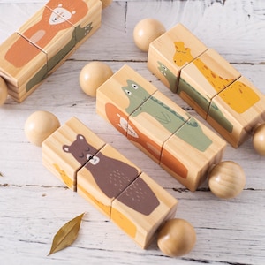Peut inclure: Des puzzles de blocs d'animaux en bois représentant un lion, une girafe, un ours, un renard et un crocodile. Chaque bloc est peint avec un animal différent et relié par des sphères en bois. Les blocs sont en bois naturel et ont des accents orange, vert et marron.