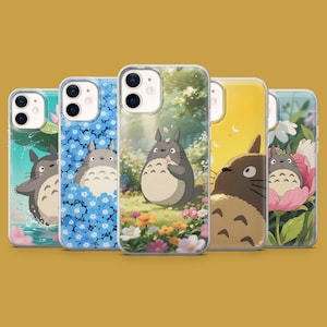 May include: A collection of five phone cases featuring illustrations of the character Totoro. The cases showcase different scenes, including Totoro in a field of flowers, in water, and in a flower. The cases have a clear, protective design.