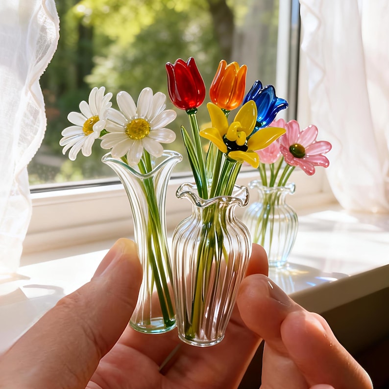 May include: A collection of miniature glass flower bouquets in clear vases. The flowers include daisies, tulips, and other colorful blooms in red, orange, yellow, blue, and pink. The vases have a ruffled rim.