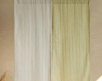 May include: Two striped curtains, one in cream with thin blue and orange stripes, the other in pale yellow with thin yellow and green stripes. The curtains are hanging from a black rod.