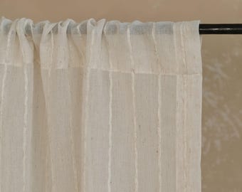 May include: Off-white linen curtain panel with vertical textured stripes. The curtain is hanging from a dark metal rod. The fabric has a slightly sheer quality, allowing some light to pass through.