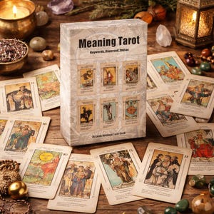 Puede incluir: Una baraja de cartas del tarot titulada "Meaning Tarot" con una caja y cartas con ilustraciones de estilo vintage. La caja muestra el título y las palabras clave. Las cartas están esparcidas sobre una superficie de madera, con velas y objetos decorativos.