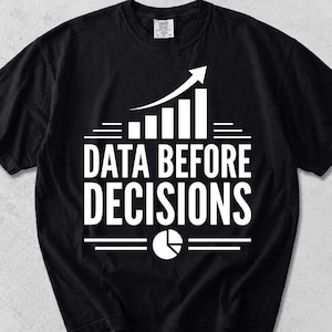 May include: A black short-sleeve t-shirt featuring a white graphic print. The design includes a bar chart with an upward-pointing arrow, the text "DATA BEFORE DECISIONS" in bold capital letters, and a circular pie chart icon at the bottom.
