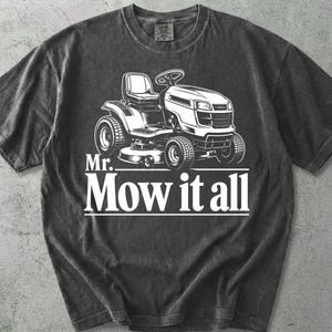 Op de afbeelding: Donkergrijs t-shirt met een witte afbeelding van een zitmaaier. De tekst "Mr. Mow it all" staat eronder gedrukt. Het shirt heeft een ronde hals en korte mouwen.