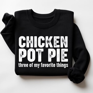 May include: Black sweatshirt with the text "CHICKEN POT PIE three of my favorite things" in white, distressed font. The sweatshirt has a crew neck and long sleeves.