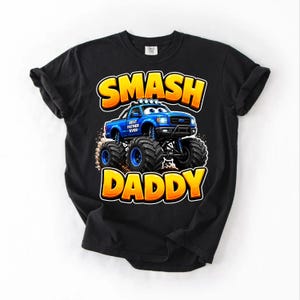 Może przedstawiać: Czarny t-shirt z niebieską grafiką monster trucka i napisem "SMASH DADDY" w kolorze ż&oacute;łtym i pomarańczowym. Samoch&oacute;d ma napis "Best Father Ever" z boku.