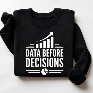 K&ouml;nnte beinhalten: Ein schwarzes Langarm-Sweatshirt mit wei&szlig;em Grafikdruck. Das Design zeigt ein Balkendiagramm mit einem aufsteigenden Pfeil, den Text "DATA BEFORE DECISIONS" in fetten Gro&szlig;buchstaben und ein kleines Tortendiagramm-Symbol am unteren Rand.