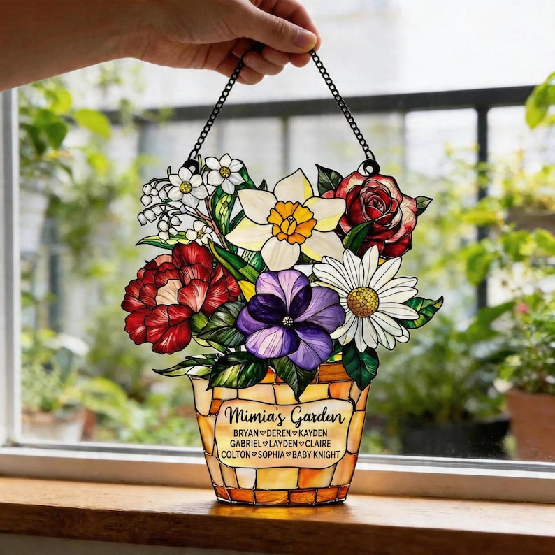 May include: Stained glass floral bouquet in a decorative pot, held by a chain. The bouquet features red, white, yellow, and purple flowers. The pot reads "Mimia's Garden" with names below.