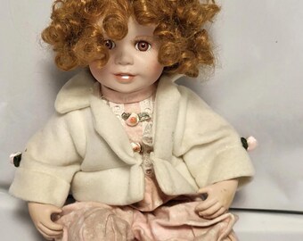 Muñeca musical de porcelana vintage de Zn con rizos dorados y vestido rosa.