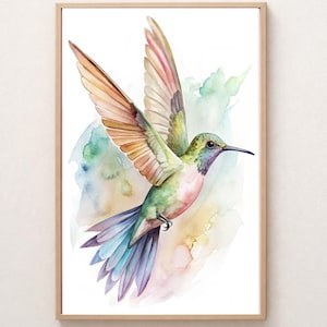 May include: Watercolor painting of a hummingbird in flight, framed in a light wood. The bird features green, pink, and purple hues, with orange and brown wings. Soft watercolor washes of blue, green, and yellow form the background.