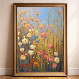 May include: An original floral oil painting in a gold frame. The artwork depicts a field of colourful flowers in shades of pink, yellow, orange, white, and blue against a light blue sky. The painting is displayed on a wooden floor.