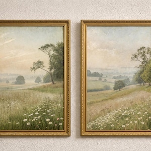 May include: Two framed landscape paintings in gold ornate frames. The artwork shows a field of wildflowers and tall grass, with trees and a hazy sky. The paintings are displayed on a textured white wall.