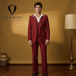 Puede incluir: Un traje de tres piezas burdeos con camisa blanca de cuello y cadena dorada. El traje incluye una americana, un chaleco y pantalones acampanados. El logotipo "APEX SUITS FORMAL SUITS FOR MAN" es visible.