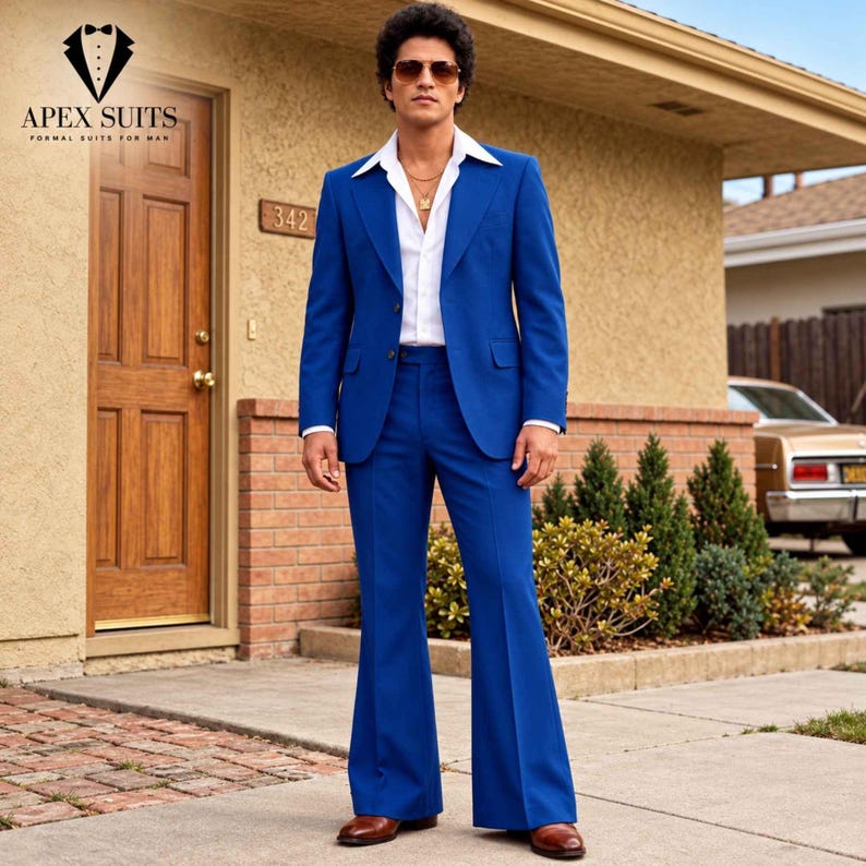 May include: A vibrant blue suit featuring a two-button blazer with wide lapels and matching flared trousers. The suit is worn over a crisp white collared shirt with an open neckline, paired with brown leather dress shoes and sunglasses.