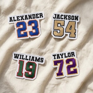 May include: Four embroidered patches featuring names and numbers. Top left: ALEXANDER 23 in blue and orange. Top right: JACKSON 54 in gold. Bottom left: WILLIAMS 19 in green and red. Bottom right: TAYLOR 72 in purple and yellow.