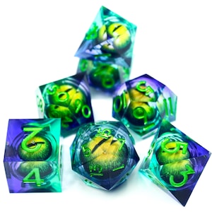 May include: Set of seven polyhedral dice with a fantasy theme. Each die is transparent with a swirling blue and green design, and a yellow eye-like core. The numbers are in green. Ideal for tabletop role-playing games.