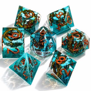 May include: A set of seven polyhedral dice made of translucent teal resin, each containing a dark brown octopus tentacle and light blue foam-like inclusions. The numbers are engraved in a metallic copper color across all the dice faces.