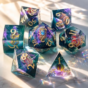 May include: Set of seven polyhedral dice with a celestial theme. The dice are clear with a teal, purple, and gold color scheme. Each die has gold numbering and a colorful, spherical design inside. Perfect for tabletop gaming.