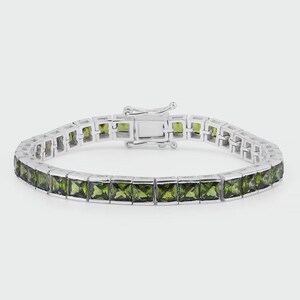 Pode incluir: Uma pulseira de prata com pedras preciosas verde-oliva de corte quadrado. A pulseira tem um fecho seguro e um design linear. As pedras preciosas são engastadas numa banda de metal prateado.