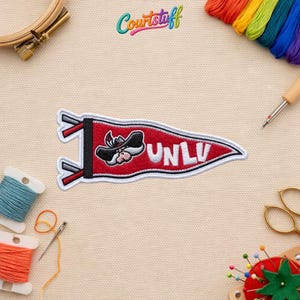 May include: A white ceramic mug with a black handle and the text "But First, Coffee" in a bold, black font. The mug is set against a blurred background, suggesting a cozy setting.