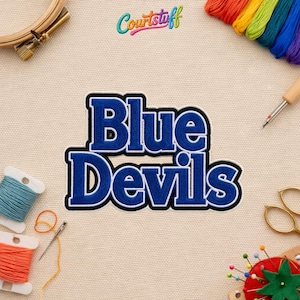 May include: A blue and white embroidered patch with the text "Blue Devils" in a bold, stylized font. The patch is surrounded by a black border and the word "Courtstuff" is in the upper left corner. Sewing supplies, including thread and scissors, are arranged around the patch.