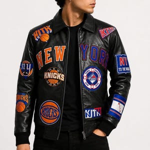 May include: A black leather jacket featuring various colorful patches and embroidery, including the text "NEW YORK", "KITH", "KNICKS", and "NY TO THE WORLD". The jacket has a collared neckline, a front zipper closure, and black ribbed cuffs at the sleeves.