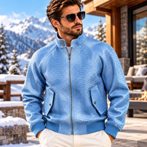 May include: A light blue jacket with a textured snakeskin-like pattern, featuring a high collar with two metal snap buttons, a central metal zip, two front pockets with snap closures, and ribbed cuffs and hem, worn with white trousers.