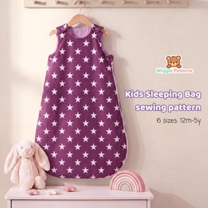 Puede incluir: Un saco de dormir sin mangas para niños de color morado con un patrón de estrellas blancas, colgado en una percha de madera. El texto dice: Wiggle Patterns, Kids Sleeping Bag sewing pattern, 6 sizes: 12m-5y. Debajo hay un conejo de peluche y un arcoíris de madera.