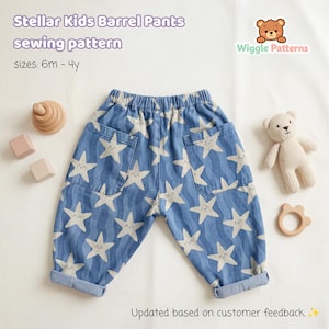 May include: Blue barrel pants with a white star pattern, featuring two front pockets. The text "Stellar Kids Barrel Pants sewing pattern" is visible. The pants are designed for sizes 6 months to 4 years. A teddy bear and wooden toys are also in the image.